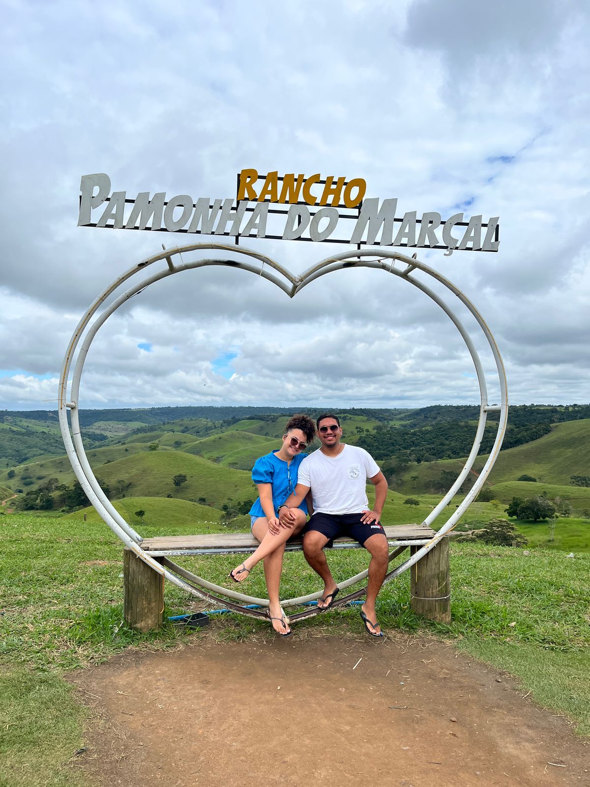Casal em um coração com paisagem verde ao fundo